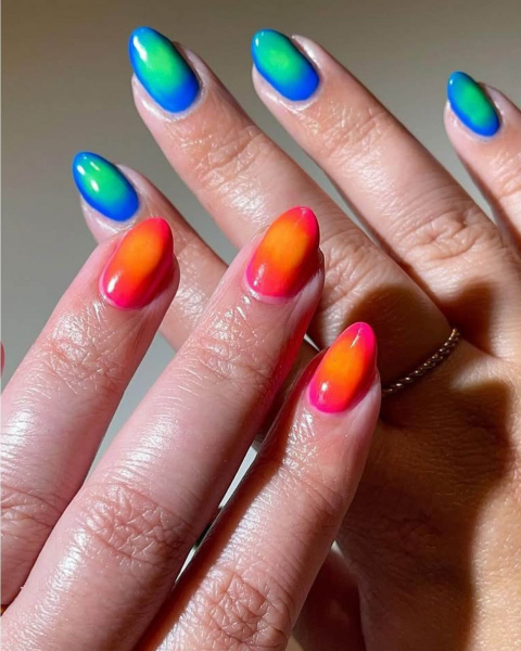Two hands one with an outward gradient from light green to blue and one layered on top with orange going into pink.
