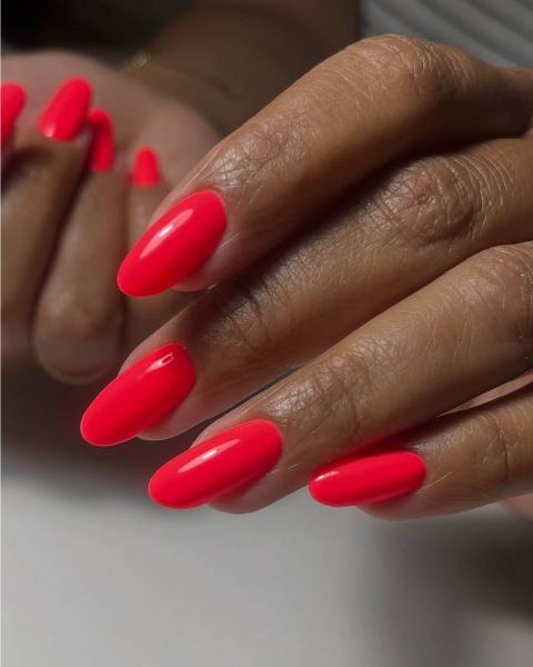 Smooth and glossy roundtip coral red neon nails.