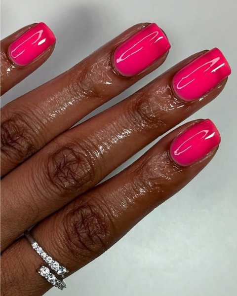 Four glossy hot pink nails with a square tip.