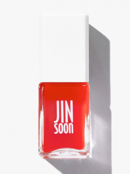 Clear nail polish bottle with cherry red polish and a white top.
