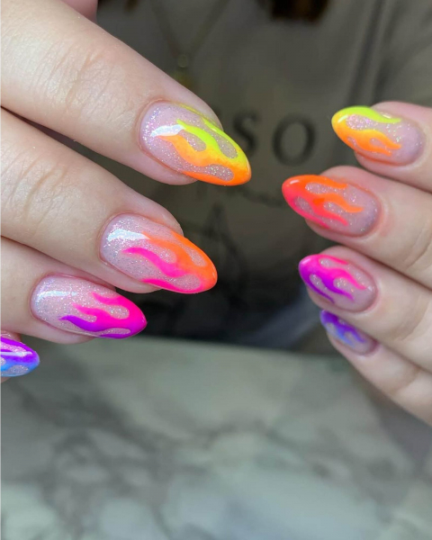 Multicolored flame French tip neon nails on glittery nude base coat.