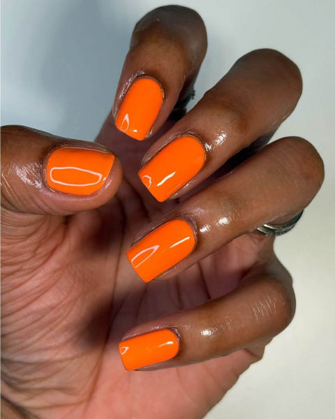 Glossy neon orange squaretip nails.