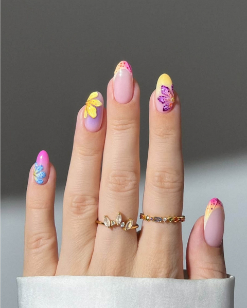 Multicolored neon and pastel ombre nails with sparkly flower designs.