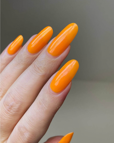 Long roundedtip neon orange tangeriney acrylic nails pointed up and out.