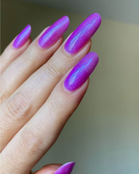Long shimmery neon purple acrylic nails with rounded tip.